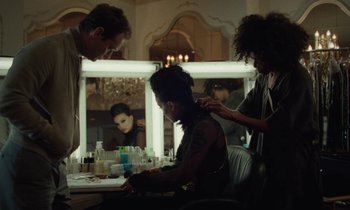 Movie still from “Vox Lux” (2018), directed by Brady Corbet – A woman getting her hair done in front of a mirror; Medium shot, Over the shoulder angle