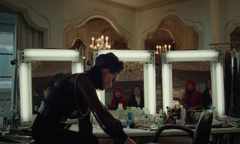 Movie still from “Vox Lux” (2018), directed by Brady Corbet – A woman in a black dress in front of a mirror; Medium shot, Over the shoulder angle