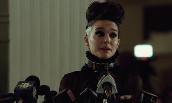 Movie still from “Vox Lux” (2018), directed by Brady Corbet – A woman in a black jacket is standing in front of microphones; Close Up shot, Over the shoulder angle