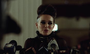 Movie still from “Vox Lux” (2018), directed by Brady Corbet – A woman in a black outfit is talking into a microphone; Close Up shot, Over the shoulder angle