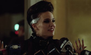 Movie still from “Vox Lux” (2018), directed by Brady Corbet – A woman in a black jacket is talking into a microphone; Close Up shot, Low angle