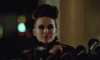 Movie still from “Vox Lux” (2018), directed by Brady Corbet – A woman with a messy hair style is standing in front of microphones and microphones; Close Up shot, Over the shoulder angle