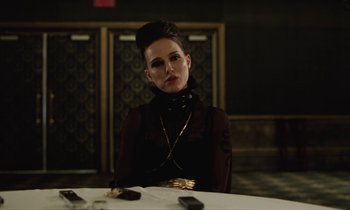 Movie still from “Vox Lux” (2018), directed by Brady Corbet – A woman sitting at a dinner table wearing a black dress; Close Up shot, Over the shoulder angle