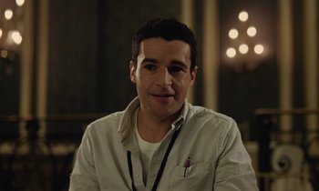 Movie still from “Vox Lux” (2018), directed by Brady Corbet – A man with a white shirt is smiling for the camera; Close Up shot, Over the shoulder angle