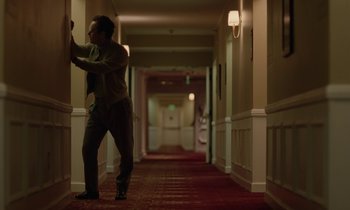 Movie still from “Vox Lux” (2018), directed by Brady Corbet – A man is standing in the hallway of a hotel room; Wide shot, Low angle