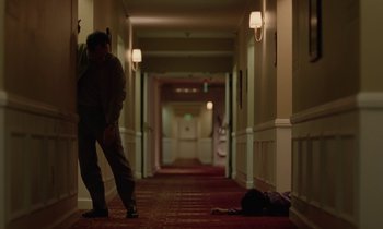 Movie still from “Vox Lux” (2018), directed by Brady Corbet – A person laying on the ground in a hallway; Wide shot, High angle