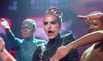 Movie still from “Vox Lux” (2018), directed by Brady Corbet – A woman in a black dress with a microphone in her mouth; Medium shot, Low angle
