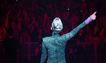 Movie still from “Vox Lux” (2018), directed by Brady Corbet – A man in a green suit waves to the crowd; Medium shot, Low angle