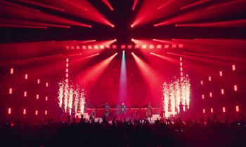 Movie still from “Vox Lux” (2018), directed by Brady Corbet – A stage lit up with red lights and people in the background; Extreme Wide shot, Low angle