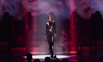 Movie still from “Vox Lux” (2018), directed by Brady Corbet – A woman in a black and silver outfit on a stage; Extreme Wide shot, Low angle