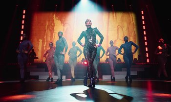 Movie still from “Vox Lux” (2018), directed by Brady Corbet – A group of people in costumes on a stage; Wide shot, Low angle