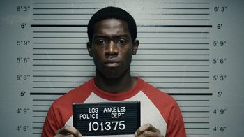 Movie still from “Snowfall” (2017), directed by Hiro Murai – A black man holding up a sign in front of his face; Close Up shot, Overhead angle
