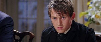 Movie still from “Wedding Crashers” (2005), directed by David Dobkin – A young man in a black jacket and a black tie; Close Up shot, Over the shoulder angle