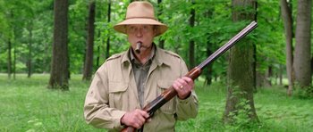 Movie still from “Wedding Crashers” (2005), directed by David Dobkin – A man holding a rifle in the woods while smoking a pipe; Medium shot, Low angle