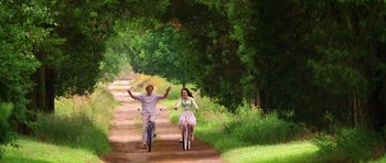 Movie still from “Wedding Crashers” (2005), directed by David Dobkin – A man and a woman riding bikes down a dirt road; Wide shot, Low angle