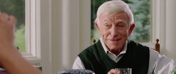 Movie still from “Wedding Crashers” (2005), directed by David Dobkin – An older man sitting at a table with a glass; Close Up shot, Over the shoulder angle