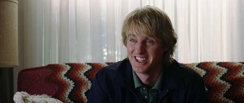 Movie still from “Wedding Crashers” (2005), directed by David Dobkin – A person sitting on a couch smiling; Close Up shot, Over the shoulder angle