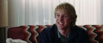 Movie still from “Wedding Crashers” (2005), directed by David Dobkin – A person sitting on a couch smiling; Close Up shot, Over the shoulder angle
