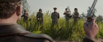 Movie still from “Welcome to Marwen” (2018), directed by Robert Zemeckis – A group of men standing next to each other in tall grass; Wide shot, Over the shoulder angle