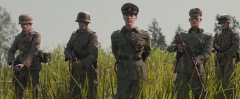Movie still from “Welcome to Marwen” (2018), directed by Robert Zemeckis – A group of men standing in tall grass; Medium shot, Low angle