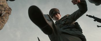 Movie still from “Welcome to Marwen” (2018), directed by Robert Zemeckis – A man wearing a uniform and a hat is throwing a ball; Medium shot, Low angle