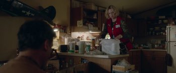Movie still from “Welcome to Marwen” (2018), directed by Robert Zemeckis – A woman in a red jacket is in a cluttered kitchen; Medium shot, Over the shoulder angle