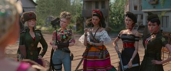 Movie still from “Welcome to Marwen” (2018), directed by Robert Zemeckis – A group of women standing next to each other holding guns; Medium shot, Low angle