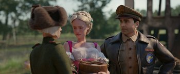 Movie still from “Welcome to Marwen” (2018), directed by Robert Zemeckis – A man and a woman standing next to each other in front of another man; Medium shot, Over the shoulder angle