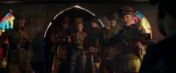 Movie still from “Welcome to Marwen” (2018), directed by Robert Zemeckis – A group of people standing next to each other under an umbrella; Medium shot, Low angle