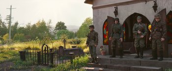 Movie still from “Welcome to Marwen” (2018), directed by Robert Zemeckis – A couple of men standing next to each other on a porch; Wide shot, Over the shoulder angle