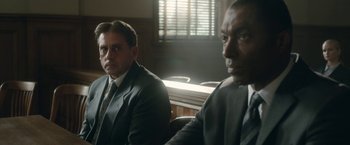 Movie still from “Welcome to Marwen” (2018), directed by Robert Zemeckis – Two men in suits sitting in a courtroom; Medium shot, Over the shoulder angle