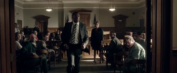 Movie still from “Welcome to Marwen” (2018), directed by Robert Zemeckis – A man and a woman are in a courtroom; Wide shot, Low angle