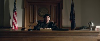 Movie still from “Welcome to Marwen” (2018), directed by Robert Zemeckis – A judge sitting at a desk in a courtroom; Medium shot, Low angle