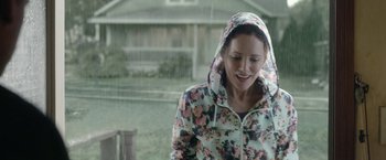Movie still from “Welcome to Marwen” (2018), directed by Robert Zemeckis – A woman in a floral print jacket standing in the rain; Medium shot, Over the shoulder angle