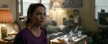Movie still from “Welcome to Marwen” (2018), directed by Robert Zemeckis – A woman sitting in front of a coffee table in a living room; Close Up shot, Over the shoulder angle