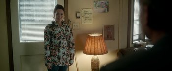 Movie still from “Welcome to Marwen” (2018), directed by Robert Zemeckis – A woman standing next to a lamp in a room; Medium shot, Over the shoulder angle