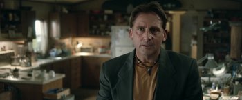 Movie still from “Welcome to Marwen” (2018), directed by Robert Zemeckis – A person wearing a suit and a necklace; Close Up shot, Over the shoulder angle