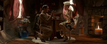 Movie still from “Welcome to Marwen” (2018), directed by Robert Zemeckis – A man kneeling down next to a woman in a hat; Wide shot, Low angle