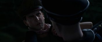 Movie still from “Welcome to Marwen” (2018), directed by Robert Zemeckis – A man in a hat is looking at another man in a uniform; Close Up shot, Over the shoulder angle