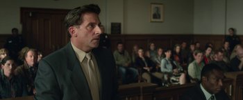 Movie still from “Welcome to Marwen” (2018), directed by Robert Zemeckis – A man standing in front of a group of people in a court room; Medium shot, Low angle