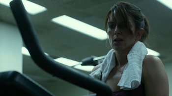 Movie still from “Whiskey Tango Foxtrot” (2016), directed by Glenn Ficarra – A woman is sitting on a stationary bike in a gym; Close Up shot, Over the shoulder angle
