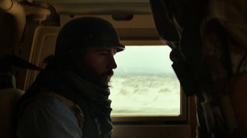 Movie still from “Whiskey Tango Foxtrot” (2016), directed by Glenn Ficarra – A man wearing a helmet looking out of a window; Close Up shot, Low angle