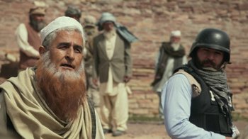 Movie still from “Whiskey Tango Foxtrot” (2016), directed by Glenn Ficarra – An old man with a long beard is standing in front of a group of men; Close Up shot, Low angle