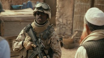 Movie still from “Whiskey Tango Foxtrot” (2016), directed by Glenn Ficarra – A man in a military uniform holding a rifle; Medium shot, Over the shoulder angle