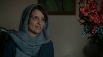 Movie still from “Whiskey Tango Foxtrot” (2016), directed by Glenn Ficarra – A woman wearing a head scarf is posing for a picture; Close Up shot, Over the shoulder angle