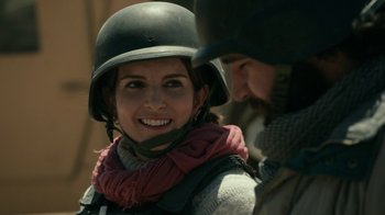 Movie still from “Whiskey Tango Foxtrot” (2016), directed by Glenn Ficarra – A woman wearing a helmet is smiling at a man; Close Up shot, Over the shoulder angle