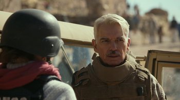 Movie still from “Whiskey Tango Foxtrot” (2016), directed by Glenn Ficarra – An older man in a military uniform talking to another man in a motorcycle helmet; Close Up shot, Over the shoulder angle