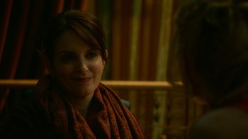 Movie still from “Whiskey Tango Foxtrot” (2016), directed by Glenn Ficarra – A woman wearing a scarf and smiling for the camera; Close Up shot, Over the shoulder angle