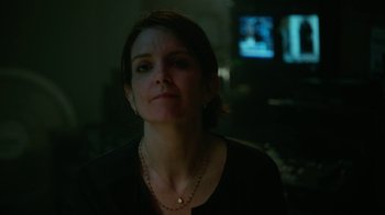Movie still from “Whiskey Tango Foxtrot” (2016), directed by Glenn Ficarra – A woman is looking at the camera in a dark room; Close Up shot, Over the shoulder angle