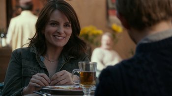 Movie still from “Whiskey Tango Foxtrot” (2016), directed by Glenn Ficarra – A woman sitting at a table with a plate of food and a glass of beer; Close Up shot, Over the shoulder angle